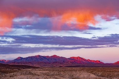 Las Vegas, Nevada, NV, ABD, ABD tarafından Mead Gölü yakınlarındaki çorak dağ manzarası üzerinde turuncu günbatımı bulutları