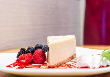 Böğürtlenli ve beyaz tabakta yaban mersinli cheesecake