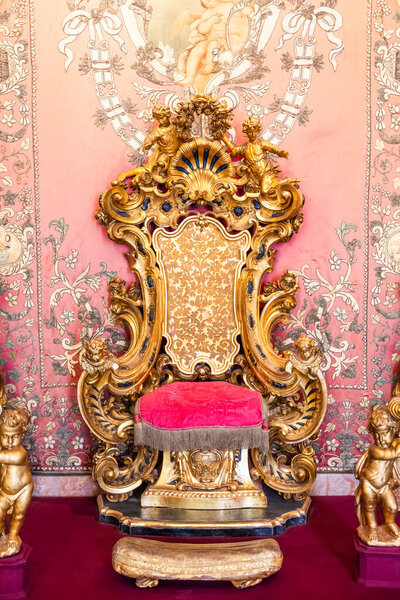 Изола Белла, Италия - 1 августа 2023 года: античный трон из золота и красного бархата. Старый королевский стул, роскошный винтаж.