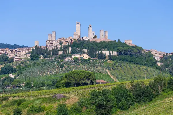 San Gimignano köyü, İtalya - yeşil kırsal bölge, mavi gökyüzü, şehir ve kuleleri olan tepe manzarası