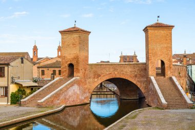 Comacchio, İtalya - 11 Haziran 2024: İtalyan kentinin tarihi sembolü ünlü Trepponti köprüsü. Liman manzarası
