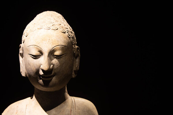 Turin, Italy - 28 December 2023: Oriental Art Museum, Standing Buddha, Northern China, late 6th c.. Copy space, black background