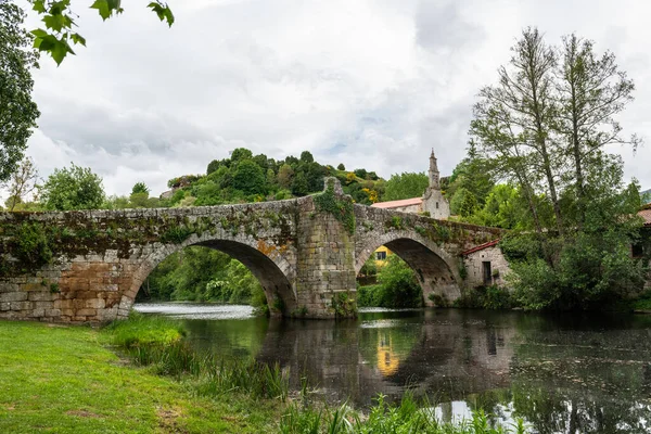Ortaçağ Roma köprüsü yağmurlu bir sabahta Galiçya 'nın Allariz köyündeki Arnoia Nehri' nin sularını yansıttı..