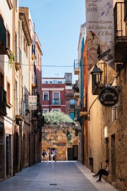 TARRAGONA, SPAIN - AUGUST 6, 2022: Narrow street in the old town of Tarragona, a tourist port city by the Mediterranean Sea in the northeast of Spain.