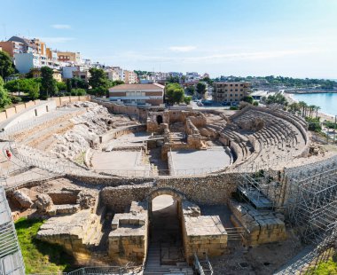 TARRAGONA, SPAIN - AUGUST 6, 2022: Wide-angle view of the ruins of the Roman amphitheater in Tarragona, built in the 2nd century AD, with the Mediterranean Sea in the background.