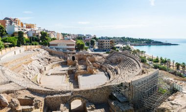 Wide-angle view of the ruins of the Roman amphitheater in Tarragona, built in the 2nd century AD, with the Mediterranean Sea in the background.