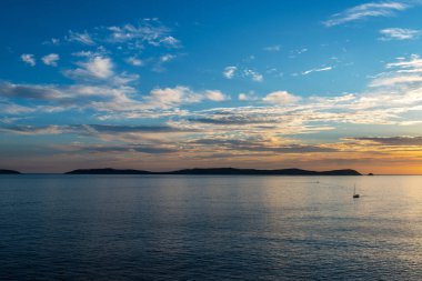 Günbatımında Galiçya 'daki Ria de Pontevedra' da Ons Adası 'ndan yalnız bir tekne denize açılır. Bu adalar 2001 yılında Avrupa Birliği tarafından kuş yaşamı için özel koruma alanı olarak belirlendi ve bir yıl sonra Atlantik Adaları 'nın bir parçası haline geldiler. 