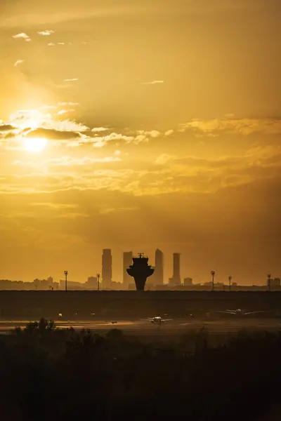 Panorama view of the T4 terminal of Madrid Barajas airport at dusk, with the skyline of the city and its four skyscrapers in the background.