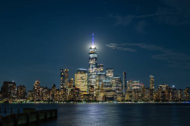 Manhattan silueti Hoboken, New Jersey 'den izleniyor, geceleri, Tek Dünya Ticaret Merkezi' nin arkasında ay var..