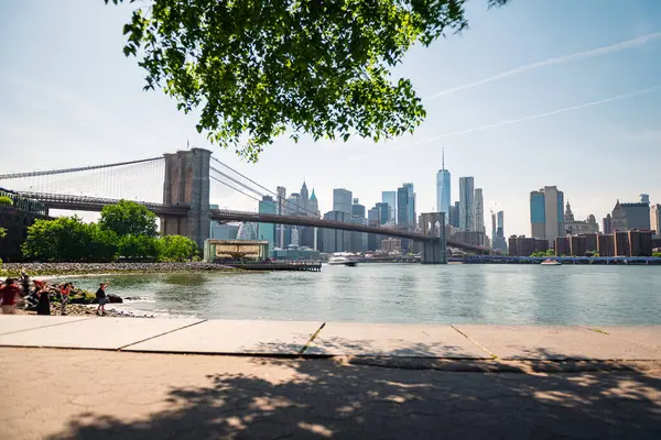 stock image Long exposure shot of the Brooklyn Bridge and New York skyline from Pebble Beach across the East River on a clear spring morning.