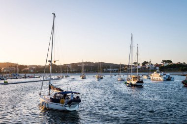 SANXENXO, SPAIN - 13 AĞUSTOS 2023: Güneşli bir yaz gününde, Portonovo yat kulübüne (Pontevedra, İspanya) demirlemiş küçük tekneler, limana giren küçük bir yelkenliyle.