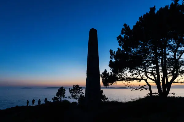 stock image Sunset falling over Ons Island in Galicia, Spain, as seen from behind a stone monolith, used in old times to measure distance and speed.