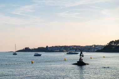 PONTEVEDRA, SPAIN - 21 Temmuz 2022: İspanya 'nın Rias Baixas şehrinde sıcak bir yaz günü Sanxenxo' daki Silgar plajına demirlemiş banyo ve küçük tekne siluetleri.