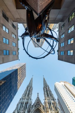 NEW YORK CITY - 19 Mayıs 2024: Manhattan, New York 'taki Atlas Heykeli ve St. Patrick Katedrali' nin alçak açılı görüntüsü.