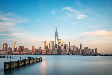 Manhattan siluetinin uzun bir görüntüsü Hoboken, New Jersey 'den alacakaranlıkta görülüyor. Sakin akşam ışığı şehrin Hudson Nehri üzerindeki ikonik gökdelenlerini güçlendiriyor..