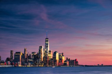 Manhattan siluetinin uzun bir görüntüsü Hoboken, New Jersey 'den alacakaranlıkta görülüyor. Sakin akşam ışığı şehrin Hudson Nehri üzerindeki ikonik gökdelenlerini güçlendiriyor..