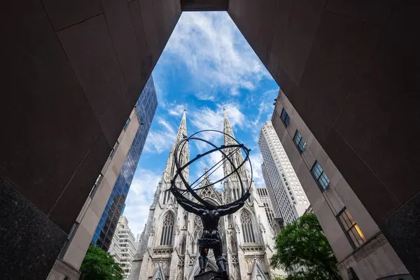 NEW YORK CITY - 25 Mayıs 2024: Manhattan, New York 'taki Atlas Heykeli ve St. Patrick Katedrali' nin alçak açılı görüntüsü.