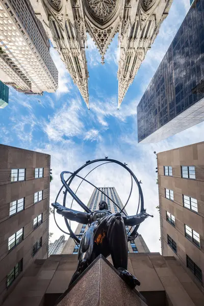 NEW YORK CITY - 25 Mayıs 2024: Manhattan, New York 'taki Atlas Heykeli ve St. Patrick Katedrali' nin alçak açılı görüntüsü.