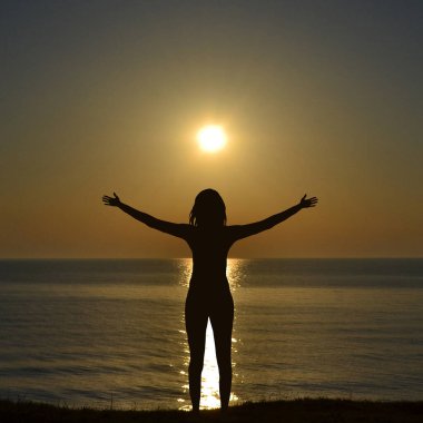 Denizde özgürlüğün tadını çıkaran bir kadın silueti.