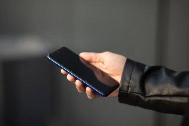 Cep telefonunu elinde tutan, internet uygulaması üzerinden sohbet eden tanınmayan bir adamın yakın plan fotoğrafı.