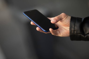 Cep telefonunu elinde tutan bir adamın internet uygulaması üzerinden sohbet ederken yakın plan fotoğrafı.
