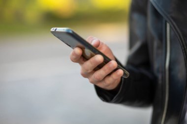 Cep telefonunu elinde tutan tanınmayan bir adam, internet uygulaması üzerinden sohbet ediyor.