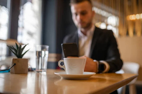 スマートフォンでニュースを読んだり 大きな白いカップから朝のコーヒーを飲む素晴らしい若い男やビジネスマン ストックフォト — ストック写真