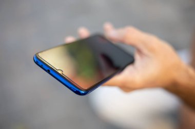 Cep telefonlu, internet ya da sosyal ağlarda arama yapan, arka planda bulanık erkek elinin yakın plan görüntüsü