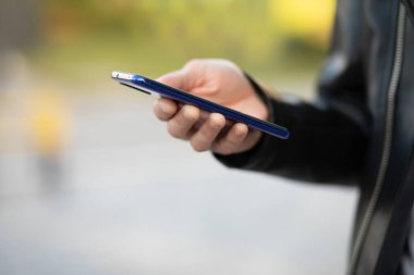 Cep telefonunu elinde tutan genç ve modern bir adamın internet uygulaması üzerinden sohbet ederken yakın plan fotoğrafı.
