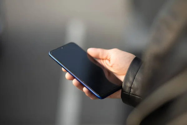 stock image Closeup shot of an unrecognizable young modern man holding mobile smartphone in hand,  chatting via internet application outdoor