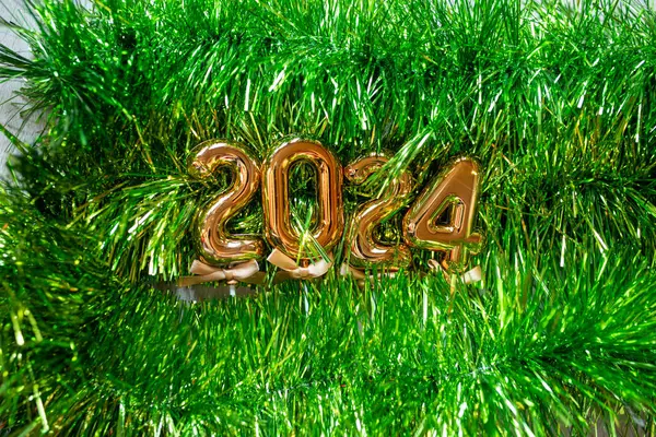 新年快乐2024 浅绿色闪光草料背景照片上的橙色金色数字 图库照片