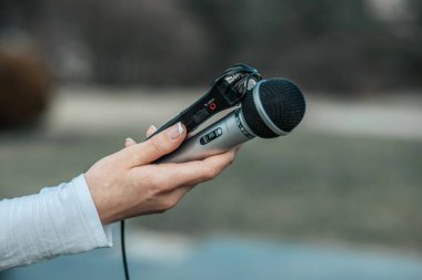 NEWS konferansında elinde mikrofon ve diktafon ses kayıt cihazı tutan gazeteci.