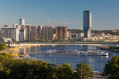 Belgrad, Sırbistan - 28 Temmuz 2024: Sava nehri üzerinde seyahat gemisi Viking Vidar, Tuna yolculuğuna devam ediyor. Arka planda modern binaların Belgrad Rıhtımı inşaat sahası yer alıyor. Belgrad Kulesi.