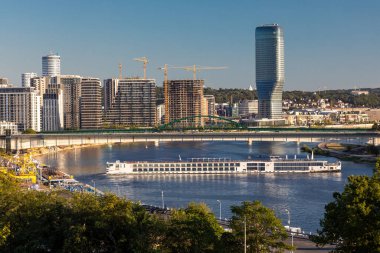 Belgrad, Sırbistan - 28 Temmuz 2024: Sava nehri üzerinde seyahat gemisi Viking Vidar, Tuna yolculuğuna devam ediyor. Arka planda modern binaların Belgrad Rıhtımı inşaat sahası yer alıyor. Belgrad Kulesi.