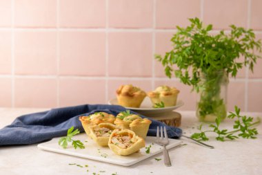 Tavuklu turtalar ve maydanoz yaprakları mutfak tezgahında beyaz seramik tabaklarda.