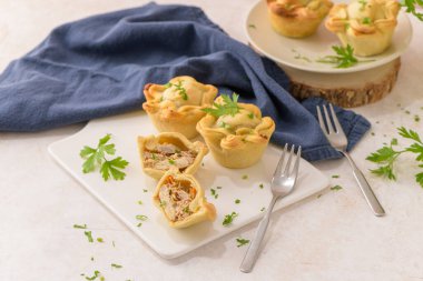 Tavuklu turtalar ve maydanoz yaprakları mutfak tezgahında beyaz seramik tabaklarda.