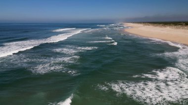 Kumlu sahil antenine çarpan dalgaların yan görüntüsü. Yukarıdan gelen boş bir sahile çarpan okyanus dalgalarının kuş bakışı görüntüsü..