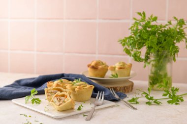 Tavuklu turtalar ve maydanoz yaprakları mutfak tezgahında beyaz seramik tabaklarda.