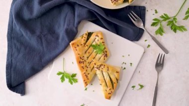 Ispanaklı puf böreği, ricotta peyniri ve maydanoz yapraklarıyla mutfak tezgahındaki beyaz seramik tabaklarda..