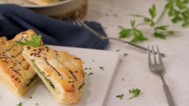 Ispanaklı puf böreği, ricotta peyniri ve maydanoz yapraklarıyla mutfak tezgahındaki beyaz seramik tabaklarda..