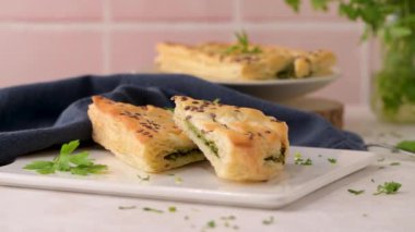 Ispanaklı puf böreği, ricotta peyniri ve maydanoz yapraklarıyla mutfak tezgahındaki beyaz seramik tabaklarda..