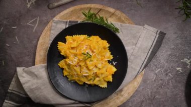 Koyu taştan mutfak tezgahında seramik tabakta kabak soslu Farfalle makarna..