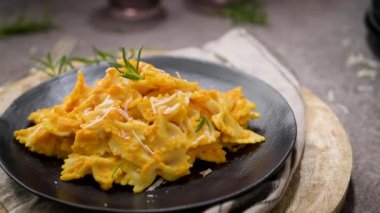Koyu taştan mutfak tezgahında seramik tabakta kabak soslu Farfalle makarna..