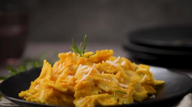 Koyu taştan mutfak tezgahında seramik tabakta kabak soslu Farfalle makarna..