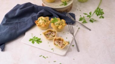 Tavuklu turtalar ve maydanoz yaprakları mutfak tezgahında beyaz seramik tabaklarda.