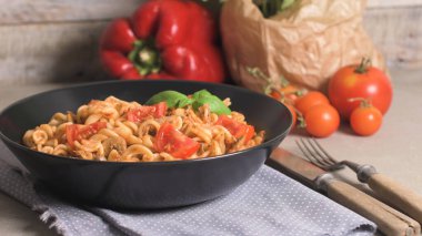 Ton balığı ve fesleğen ile İtalyan makarna. Eski ahşap arka plan üzerinde ton balığı ve domates soslu makarna.