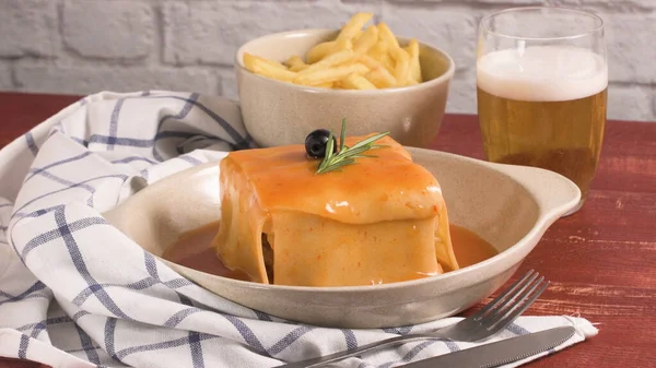 传统的葡萄牙小吃食品 Francesinha 三明治的面包 番茄啤酒酱和薯条 还有啤酒和马铃薯桌上 — 图库照片