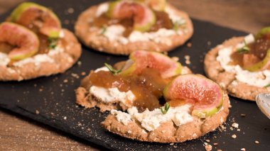 Kanepe veya crostini ile krem peynir ve incir ile tahıllı crispread jam kayrak bir gemide. Lezzetli meze bir aperatif ideal.