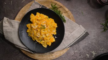 Koyu taştan mutfak tezgahında seramik tabakta kabak soslu Farfalle makarna..
