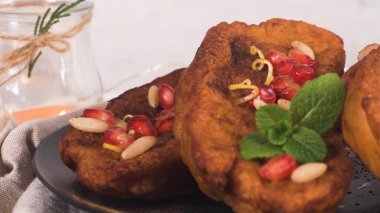 Traditional Christmas Rabanadas with pommegranate seeds, pine nuts and cinnamon. Spanish Torrijas or french toasts close up on the countertop.